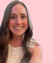A woman with long brown hair smiles warmly, wearing a necklace, reflecting joy and positivity, aligning with WeNatal's nurturing ethos.